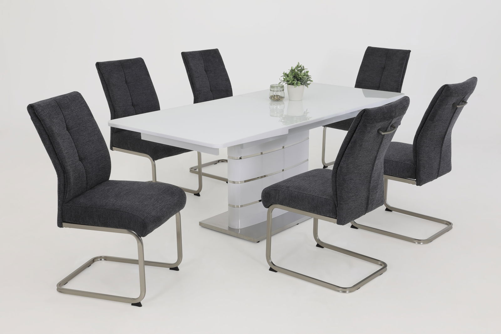Esszimmer mit sechs modernen Schwingstühlen in Dunkelgrau um einen weißen Tisch, seitliche Perspektive.