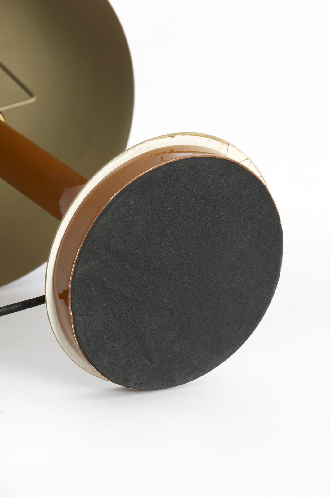 Nahaufnahme der Unterseite einer Tischleuchte mit runder, schwarzer Basis und braunem Stiel.