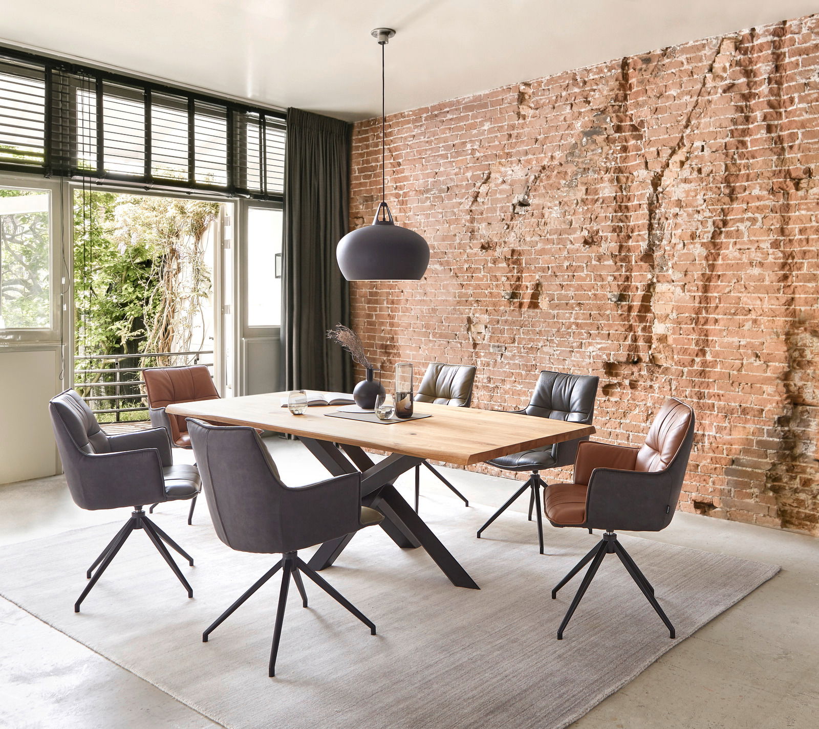 Esszimmer mit modernem Tisch und Sesseln vor einer Ziegelwand, Perspektive von schräg vorne