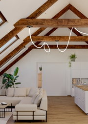 Een moderne installatie met led-lichtslingers in een stijlvolle woonkamer met houten balkenplafond, gezien vanuit een laag standpunt.