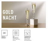 Zwei elegante Champagnergläser mit goldenen Verzierungen, eines auf einem weißen Sockel, seitliche Perspektive.