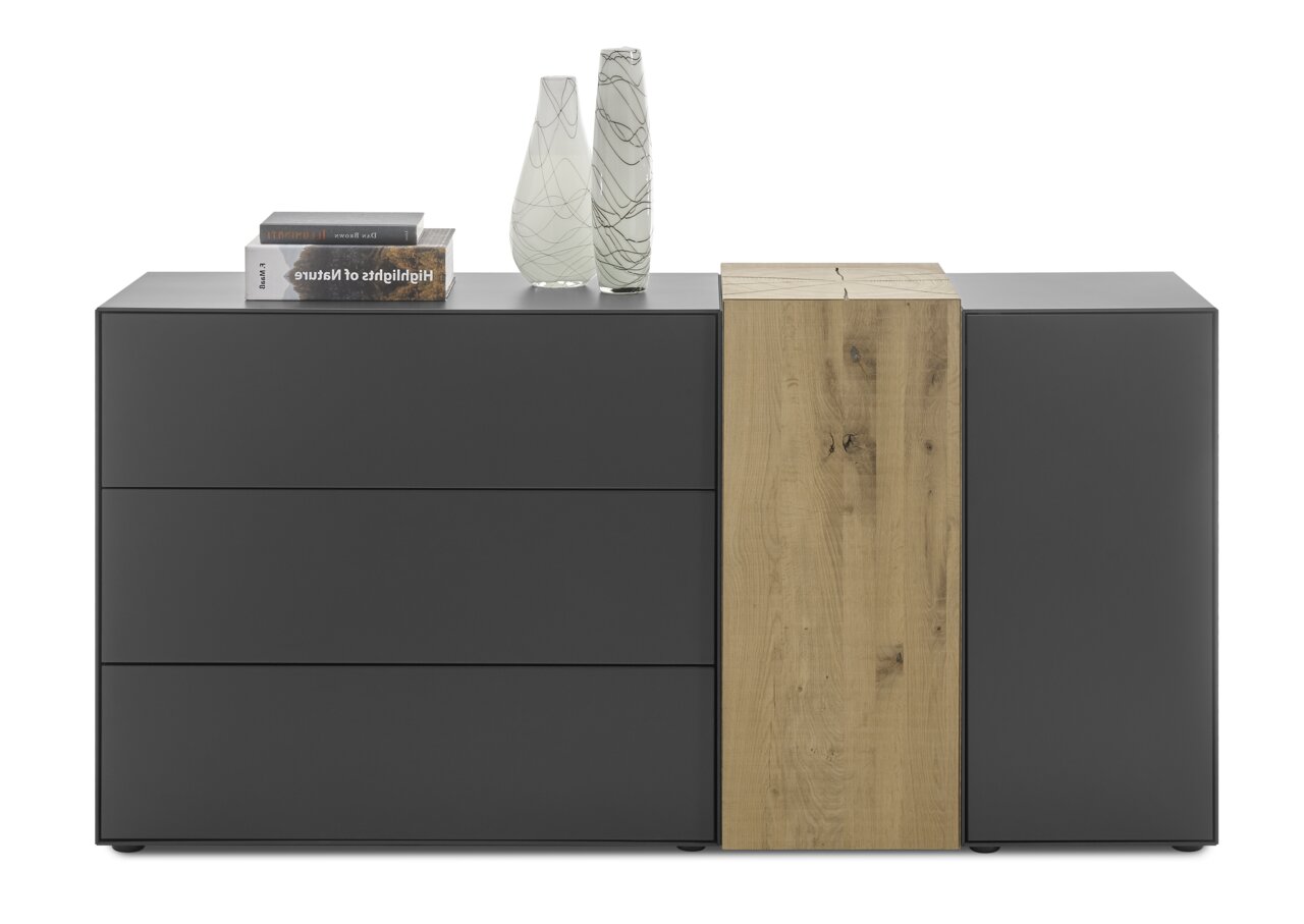 Modernes Sideboard in dunklem Grau mit drei Schubladen und einem Holzabschnitt, dekoriert mit zwei Vasen und Büchern, frontal betrachtet.