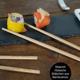 Sushi-Set mit Schieferplatte und Bambusstäbchen, von oben fotografiert.