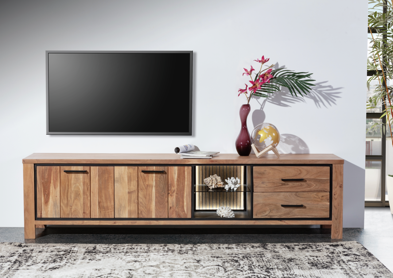 Frontale Ansicht eines Lowboards aus Holz mit zwei Türen, zwei Schubladen und einem offenen Fach mit Beleuchtung, dekoriert mit einer Vase, einem Globus und Zeitschriften.