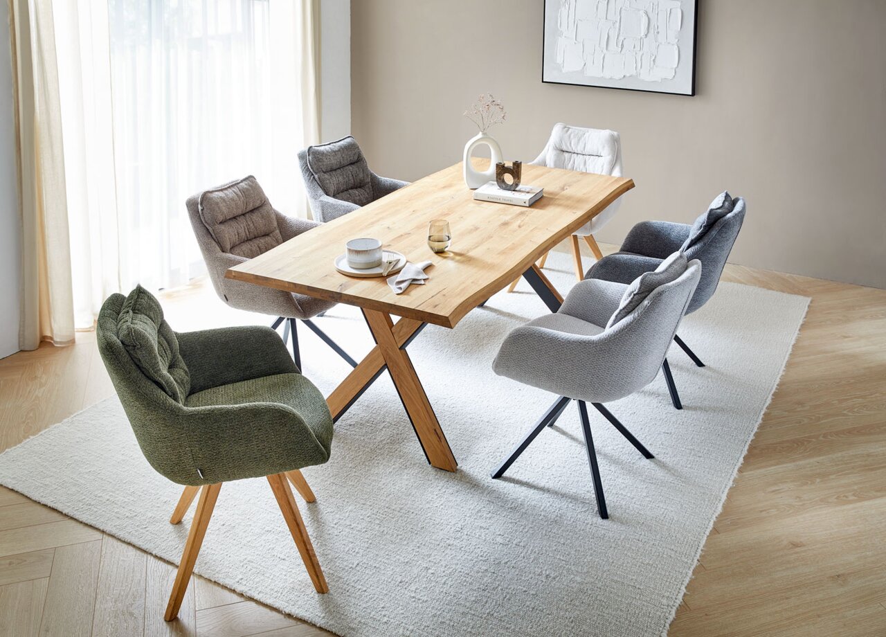 Linea Natura Armlehnstuhl COMO Esszimmer mit einem Holztisch und mehreren gepolsterten Armlehnstühlen in verschiedenen Farben, aus der Vogelperspektive betrachtet.