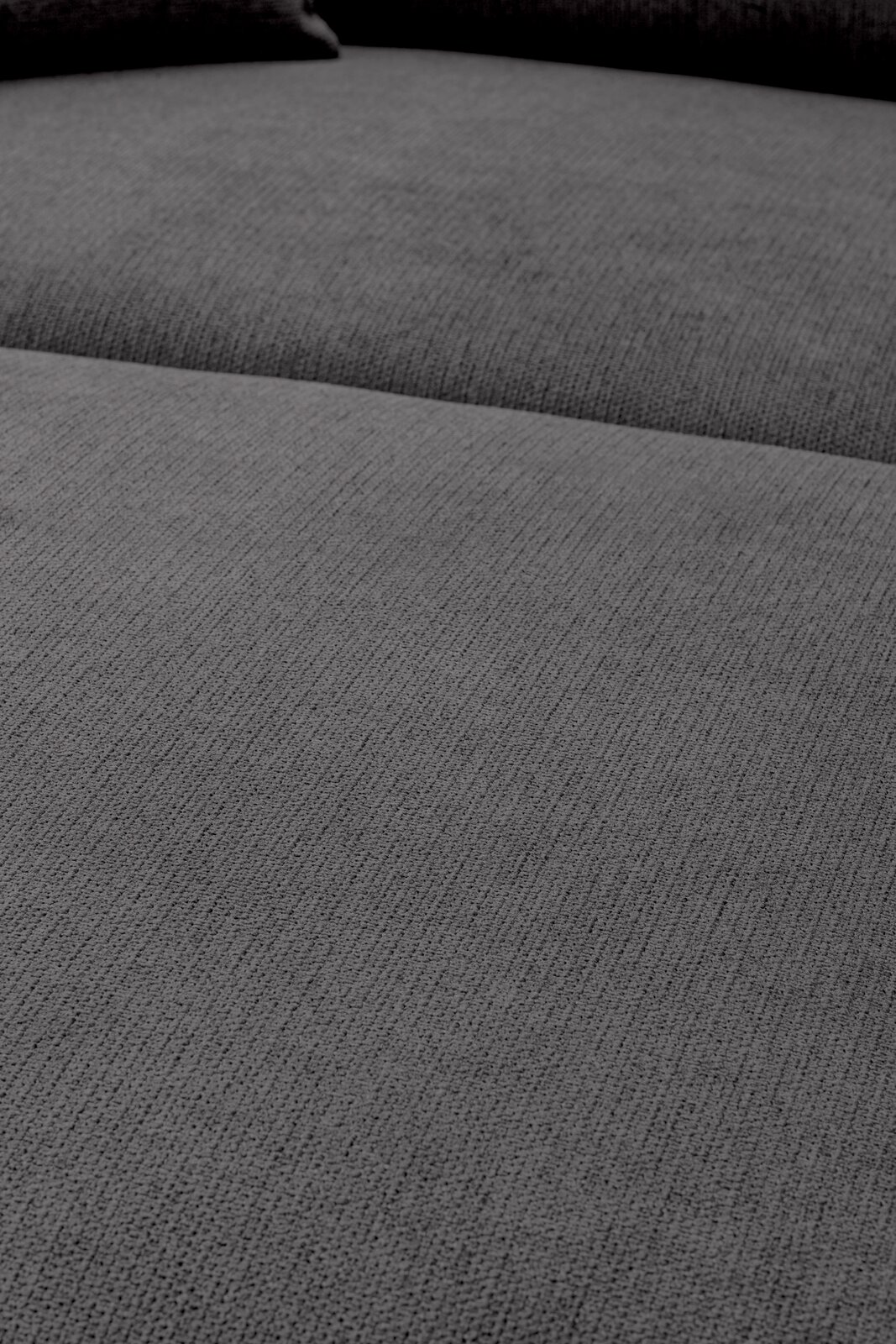Nahaufnahme der grauen, fein strukturierten Stoffpolsterung eines Sofas/Polstermöbels, Perspektive: schräg von oben auf die Sitzfläche.