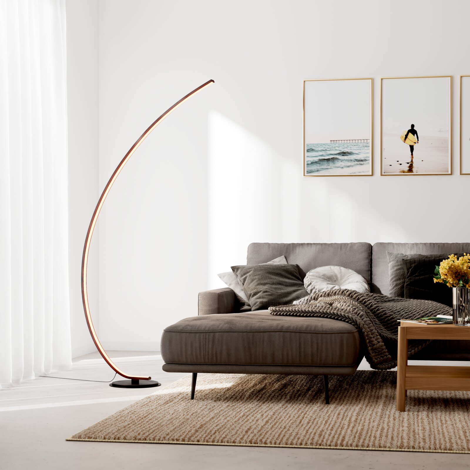 Moderne bogenförmige LED-Stehlampe mit warmem Licht auf schwarzem Rundfuß neben grauem Sofa im Wohnzimmer, Frontansicht leicht seitlich von links
