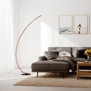 Moderne bogenförmige LED-Stehlampe mit warmem Licht auf schwarzem Rundfuß neben grauem Sofa im Wohnzimmer, Frontansicht leicht seitlich von links