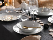 Elegantes Tellerset 18-tlg auf einem festlich gedeckten Tisch mit goldfarbenem Besteck und Gläsern, seitliche Perspektive