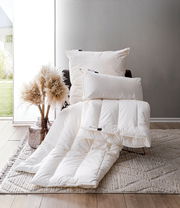 Vegan Dream Duobett 155x220cm in einem modernen Raum, mit Kissen und Decke auf einem Sessel arrangiert, seitliche Perspektive.