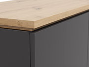 Nahaufnahme eines Highboards mit einer Kombination aus einer dunklen, glatten Oberfläche und einer hellen Holzplatte, Perspektive von oben.
