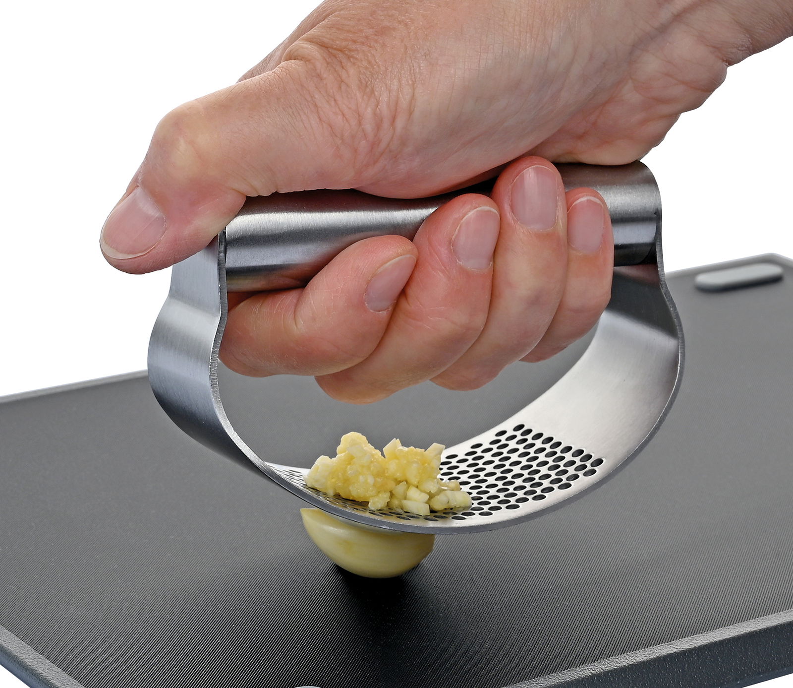 Nahaufnahme einer Hand, die eine Knoblauchpresse aus Edelstahl bedient, um frischen Knoblauch zu pressen. Die Perspektive zeigt die Presse von der Seite.