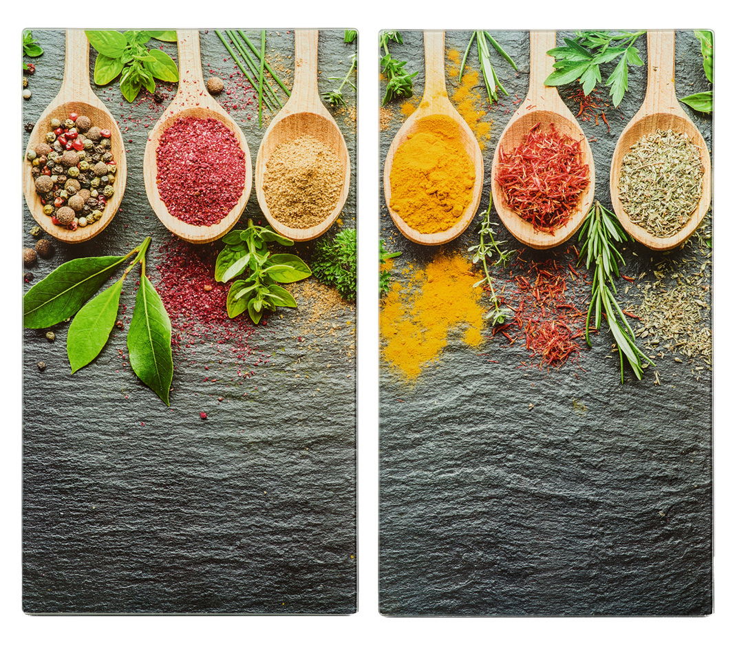 Zwei Herdabdeck- und Schneideplatten mit bunten Gewürzen und Kräutern auf Holzlöffeln, aus der Vogelperspektive fotografiert.