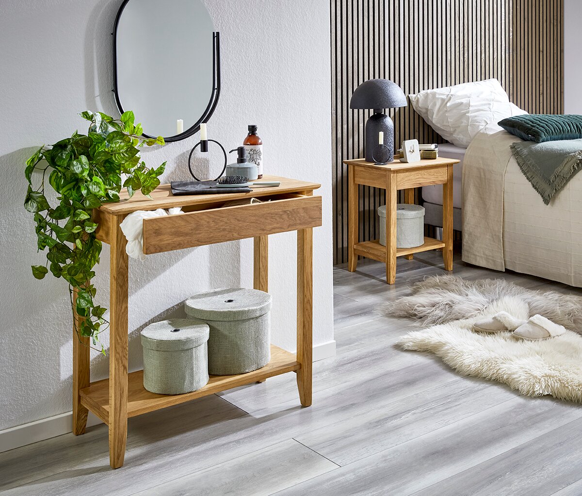 Schmaler Konsolentisch aus hellem Holz mit Schublade und Ablage, dekoriert mit Pflanze und Accessoires, im Schlafzimmer-Setting neben einem Nachttisch; Perspektive: leicht seitliche Frontansicht auf Augenhöhe.