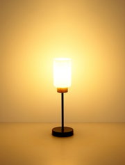 Moderne Tischlampe mit zylindrischem, weißem Glasschirm, schwarzem Stab und rundem Sockel mit Holzakzent, warm leuchtend vor neutralem Hintergrund, Frontalansicht
