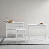 Drei weiße Möbelstücke auf einem Teppich vor einer hellen Wand, bestehend aus einer Kommode, einem Konsolentisch und einer Nachtkonsole, frontal betrachtet.