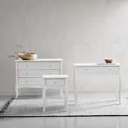 Drei weiße Möbelstücke auf einem Teppich vor einer hellen Wand, bestehend aus einer Kommode, einem Konsolentisch und einer Nachtkonsole, frontal betrachtet.