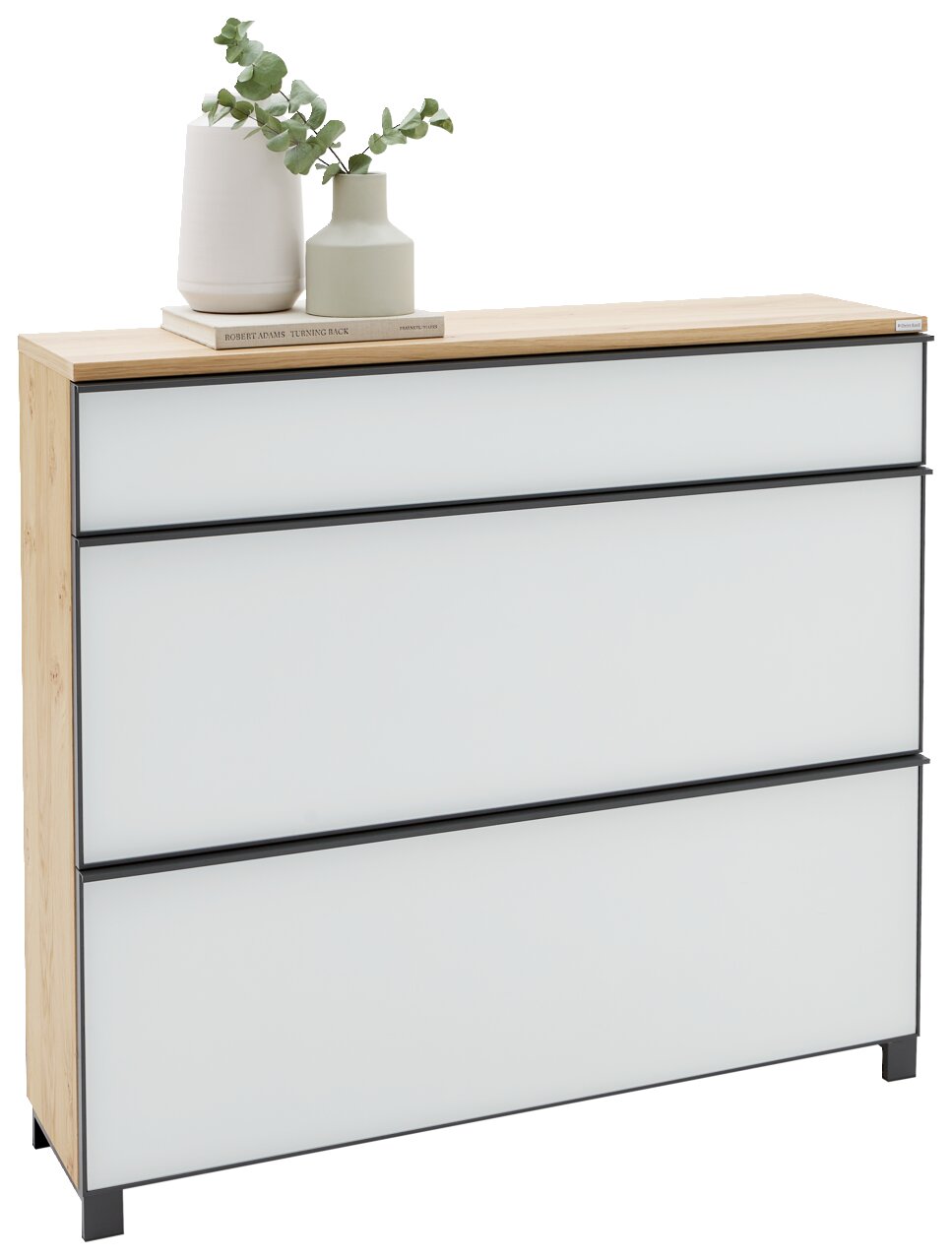Moderne Kommode mit drei weißen Schubladen, schwarzem Rahmen und Holzplatte, dekoriert mit Vasen und Buch, in leicht schräger Frontansicht von links