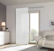Moderner, weißer Fertigvorhang Esposa vor einer großen Fensterfront in einem hellen Wohnzimmer, seitliche Perspektive.