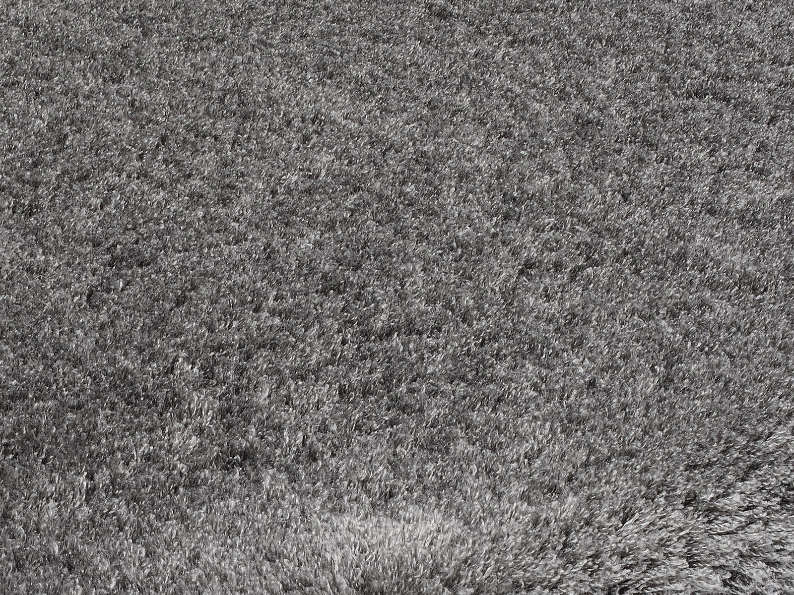 Grauer Hochflor-Teppich in Nahaufnahme, der die weiche und flauschige Textur des Materials zeigt.