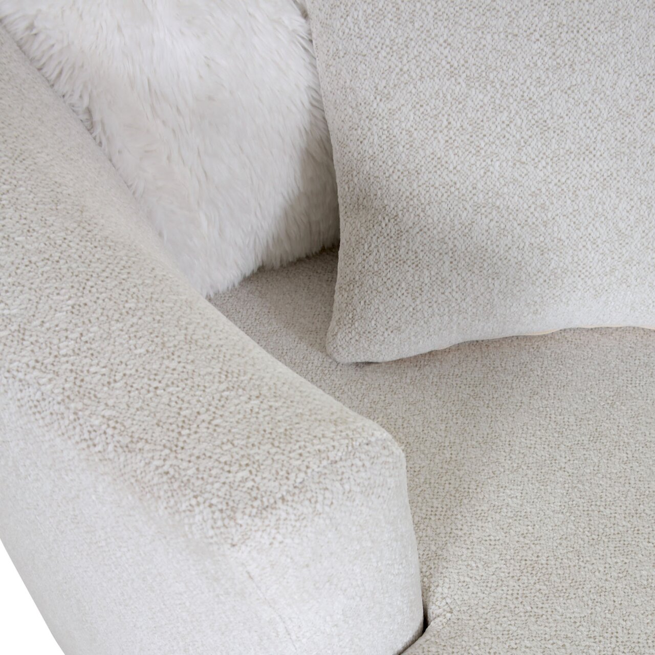 Nahaufnahme eines beigen Sessels mit weicher Textur, Kissen und flauschiger Decke, von oben betrachtet.