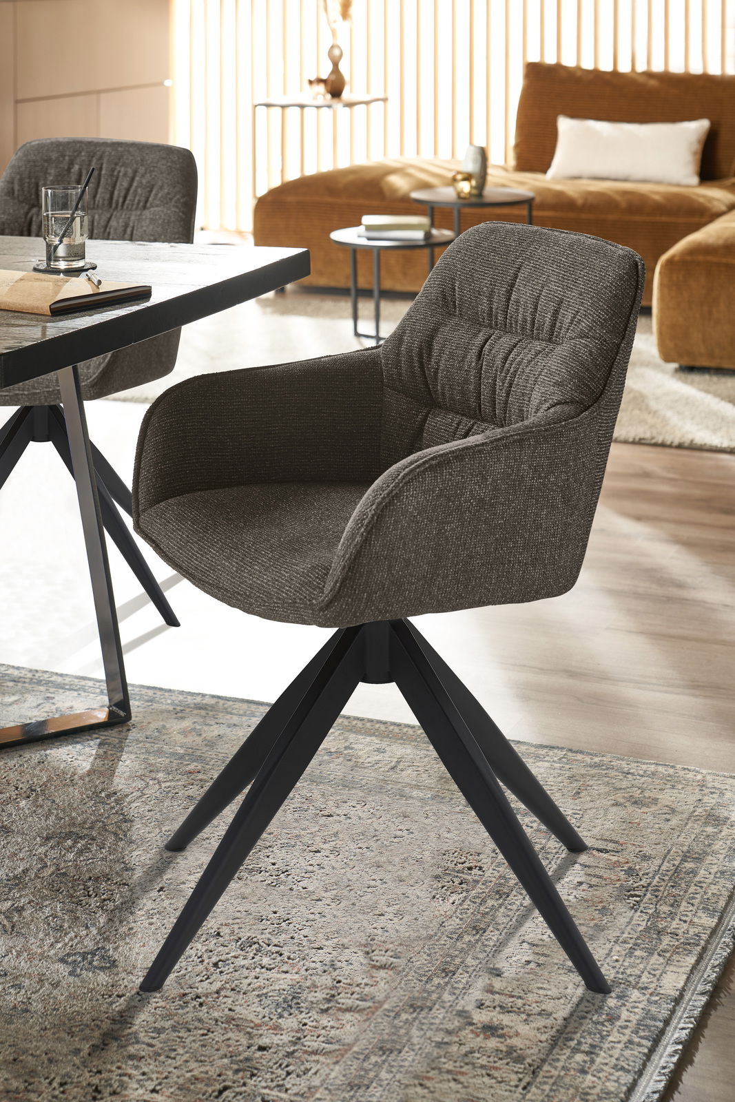 Moderner Armlehnstuhl mit dunklem Stoffbezug und schwarzem Metallgestell, seitliche Perspektive