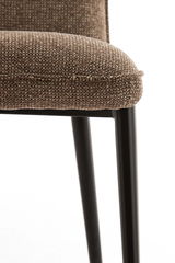 Nahaufnahme eines Stuhls mit braunem, strukturiertem Stoffbezug und schwarzen Metallbeinen, seitliche Perspektive.