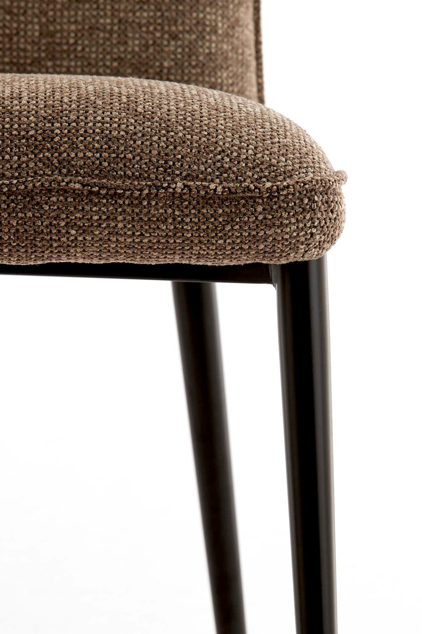 Close-up van een stoel met een bruine, gestructureerde stoffen bekleding en zwarte metalen poten, gezien vanaf de zijkant.