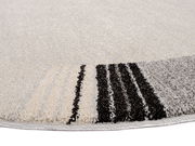 Nahaufnahme eines runden Frisé-Teppichs mit cremefarbenem Hintergrund und schwarzen sowie grauen Streifen am Rand, aus seitlicher Perspektive aufgenommen.