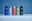 Fünf Sporttrinkflaschen in verschiedenen Farben (blau, hellblau, rosa, grün, grau) in einer frontalen Perspektive auf einem blauen Hintergrund.