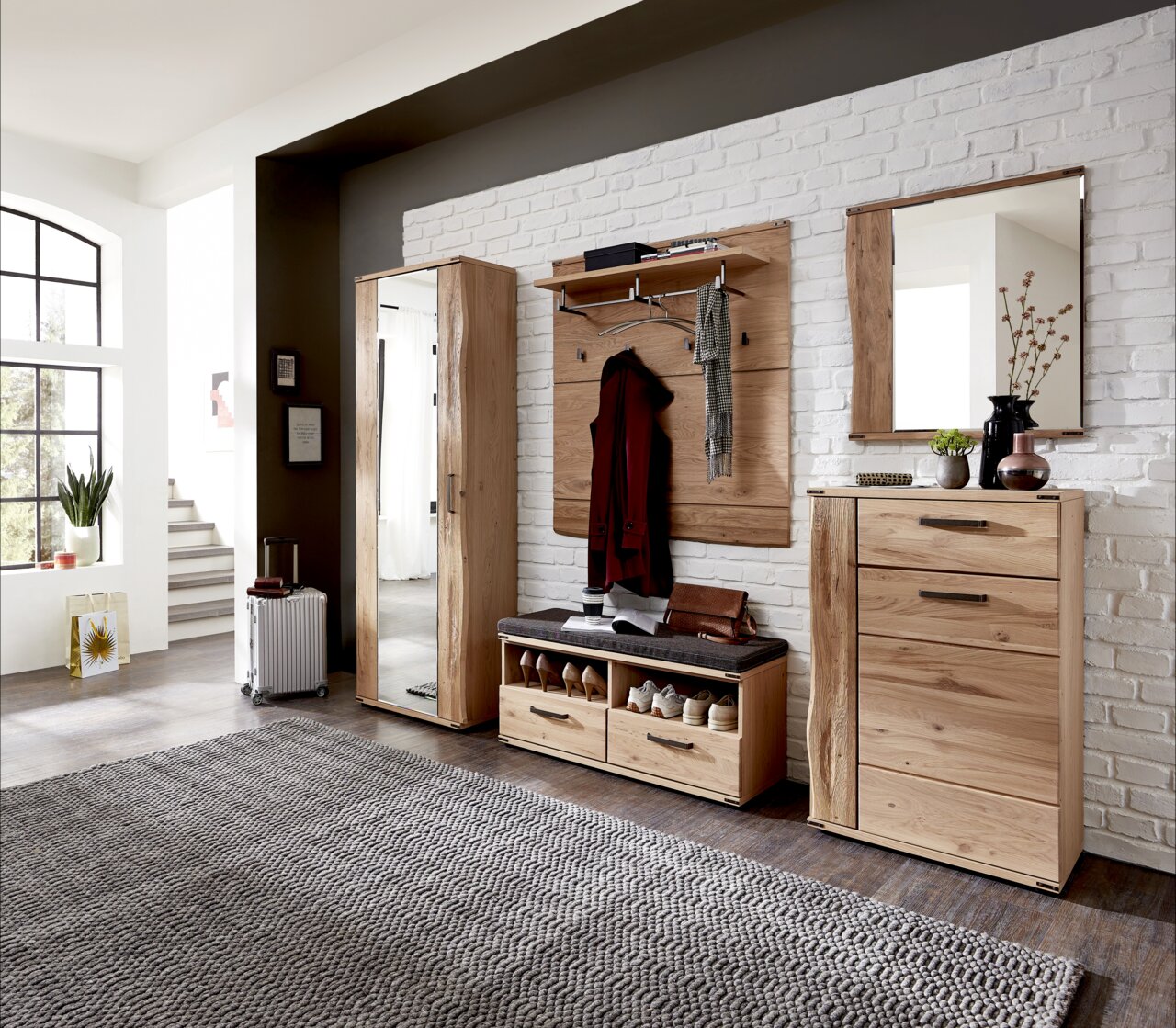 Moderne Garderobenkombination aus Holz in einem hellen Raum, bestehend aus Garderobenschrank, Schuhschrank, Garderobenpaneel, Spiegel und Garderobenbank. Frontalansicht.