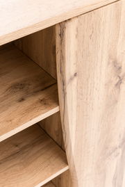 Nahaufnahme eines Unterschranks aus Holz mit sichtbaren Regalböden und natürlicher Holzmaserung, Perspektive von schräg oben.