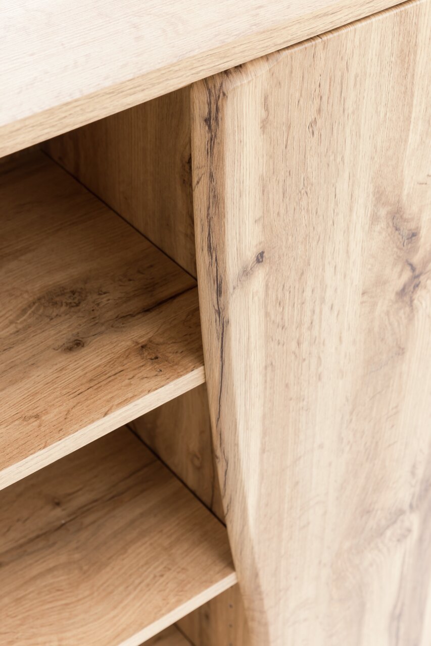 Nahaufnahme eines Unterschranks aus Holz mit sichtbaren Regalböden und natürlicher Holzmaserung, Perspektive von schräg oben.