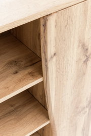 Nahaufnahme eines Unterschranks aus Holz mit sichtbaren Regalböden und natürlicher Holzmaserung, Perspektive von schräg oben.