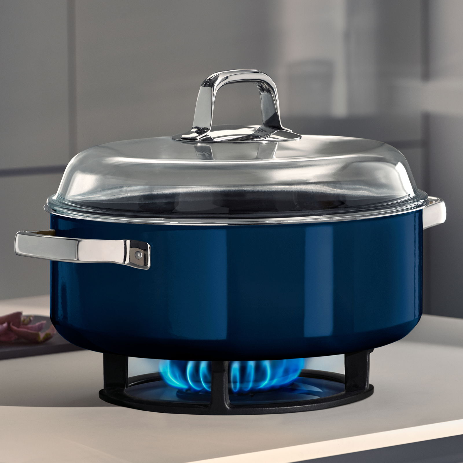 WMF Schmortopf mit Deckel Ø28cm FUSIONTEC MINERAL PRO Blauer Schmortopf mit Glasdeckel, seitliche Perspektive, auf einem Herd mit blauer Flamme