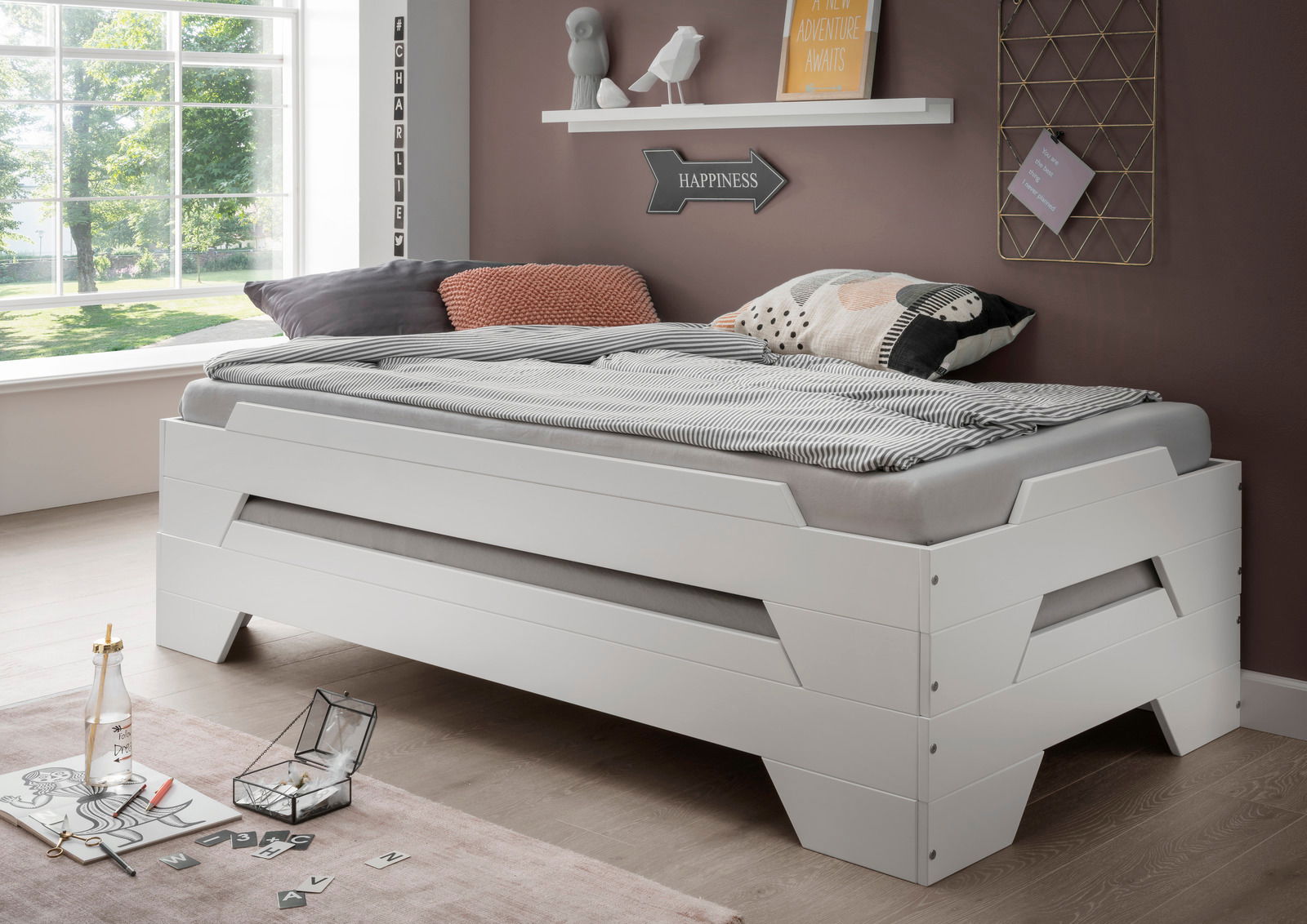 Stapelbett in modernem Design, seitliche Perspektive, mit gemütlicher Bettwäsche und dekorativen Kissen in einem hellen Raum.