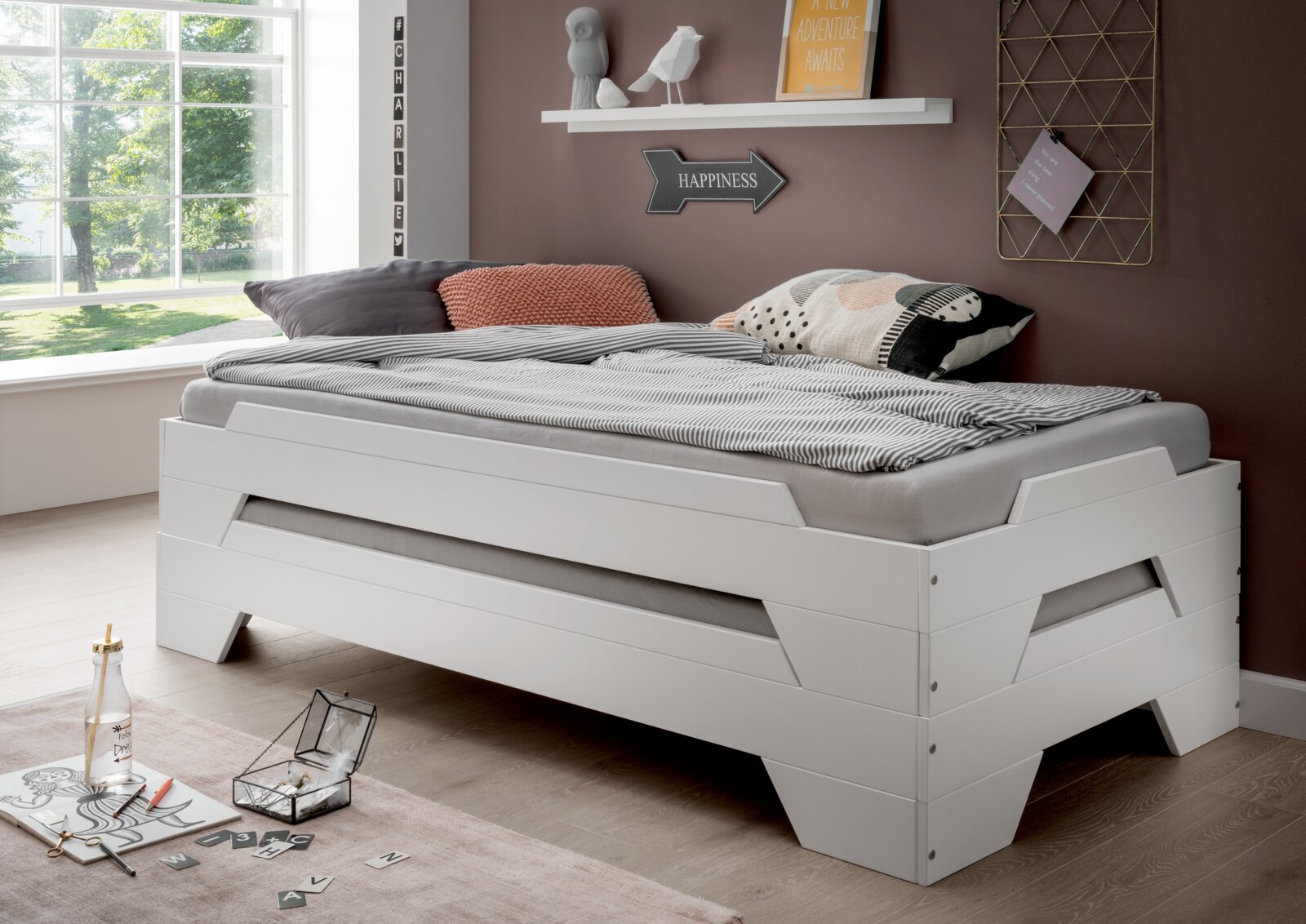 Stapelbett in modernem Design, seitliche Perspektive, mit gemütlicher Bettwäsche und dekorativen Kissen in einem hellen Raum.