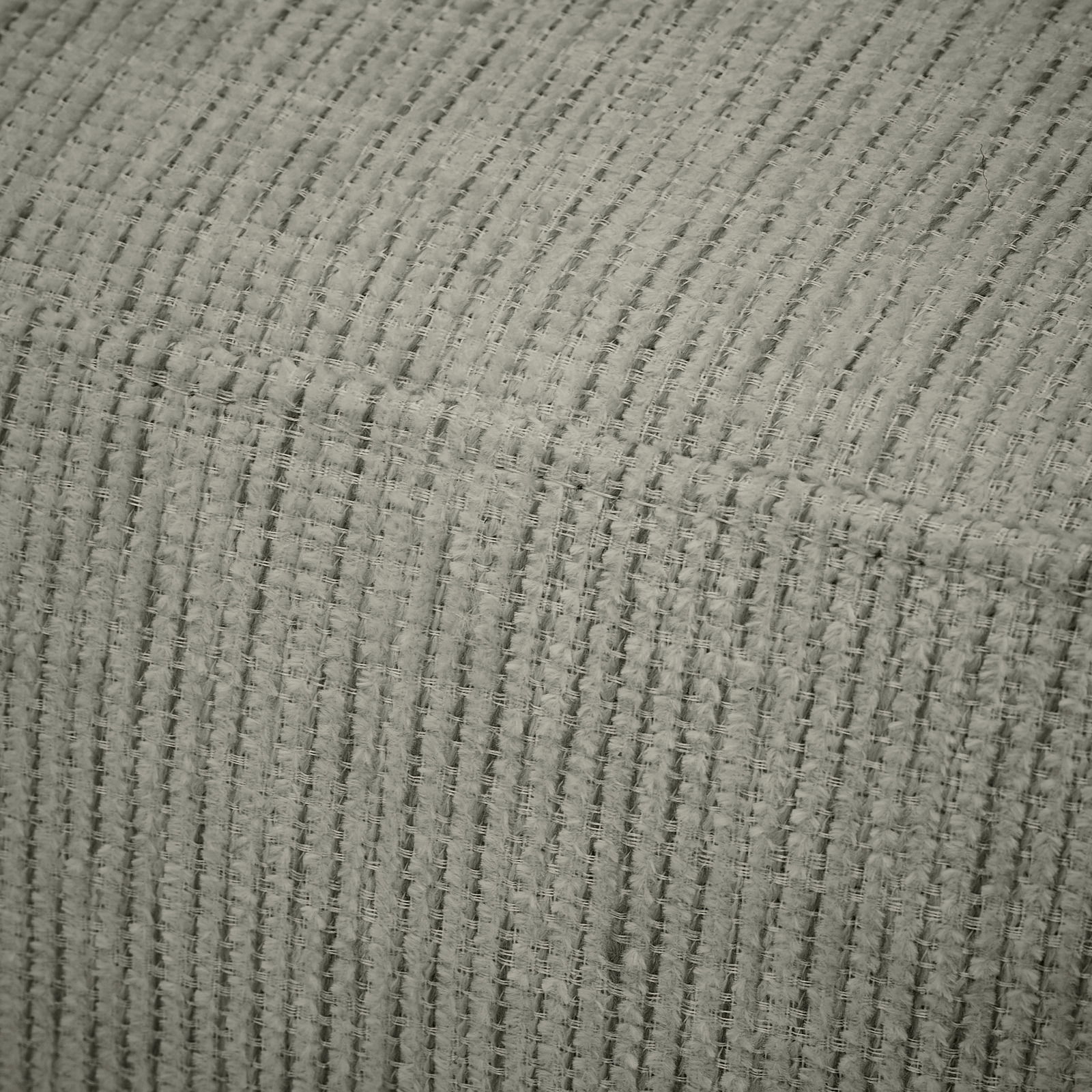 Nahaufnahme eines strukturierten Stoffes in Grau, perspektivisch von oben fotografiert.
