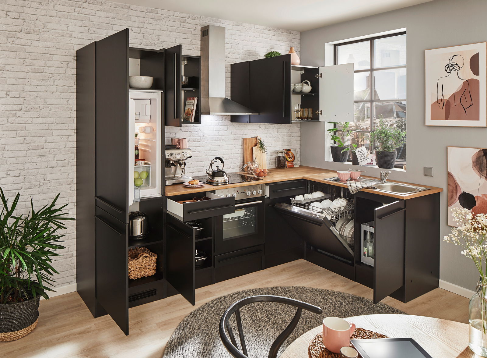 Moderne schwarze Küche mit Eckunterschrank, Kühlschrank, Backofen, Geschirrspüler und Spüle, aus der Perspektive eines offenen Raumes mit Blick auf die Arbeitsfläche und Geräte.