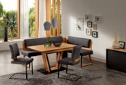 Moderne Esszimmer-Einrichtung mit Holztisch, Eckbank und Freischwinger-Stühlen in einem hellen Raum mit großen Fenstern, von schräg vorne betrachtet.