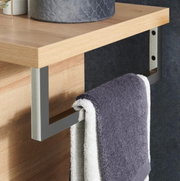 Nahaufnahme eines modernen Handtuchhalters aus Metall, montiert an einem Holzregal, mit einem grauen Handtuch. Perspektive von der Seite.
