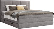 Grijs gestoffeerd boxspringbed met hoog, gewatteerd hoofdbord en beddengoed, schuin van voren in 3/4-perspectief weergegeven op witte achtergrond