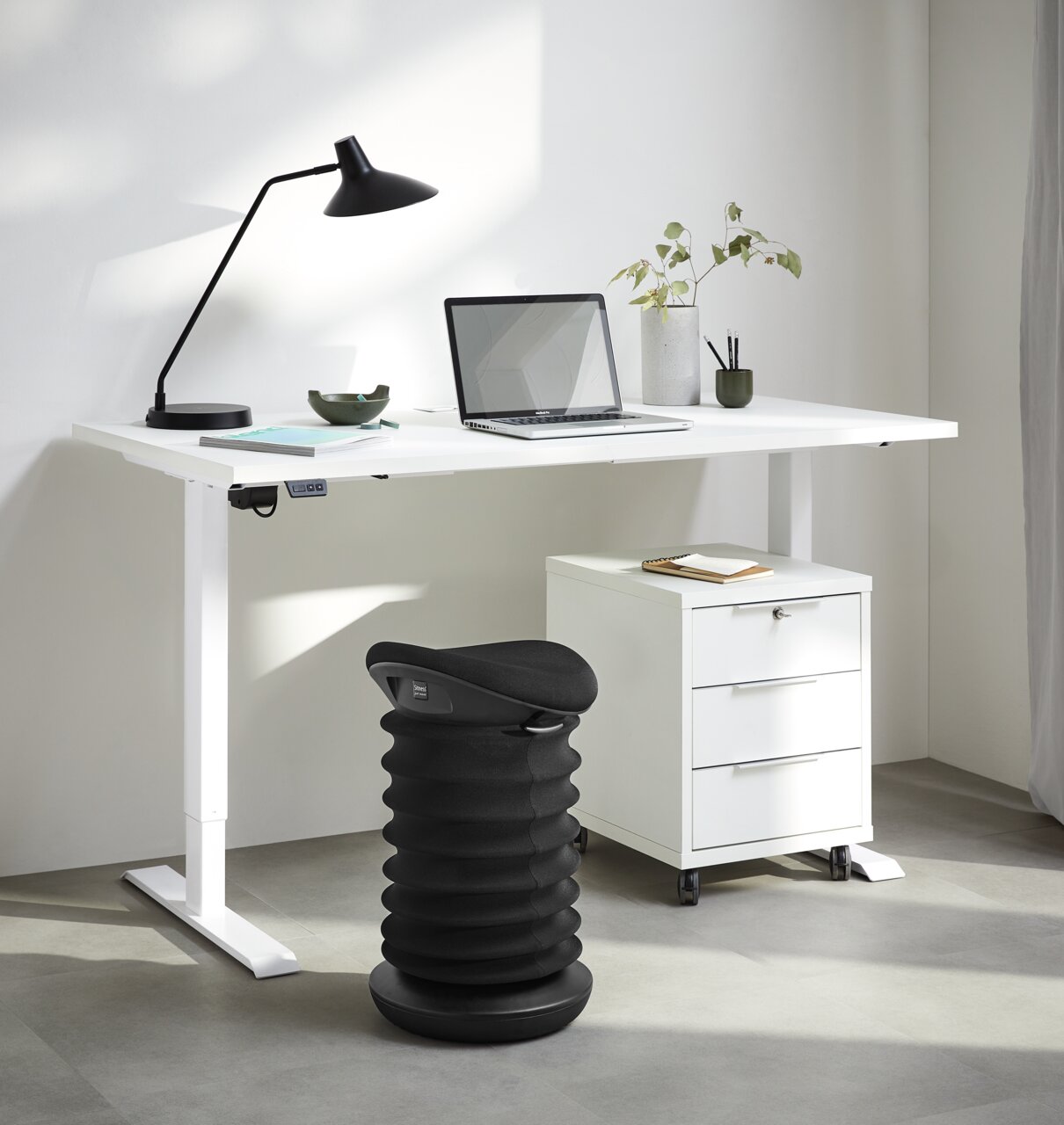 Sitness Schwinghocker 4D Schwarzer Schwinghocker in einem modernen Büro, seitliche Perspektive