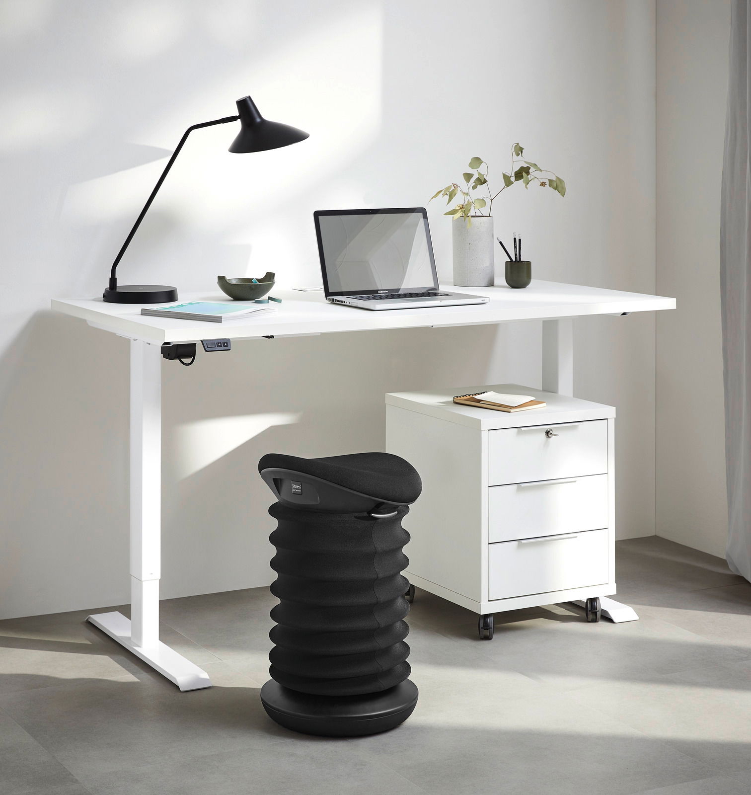 Sitness Schwinghocker 4D Schwarzer Schwinghocker in einem modernen Büro, seitliche Perspektive