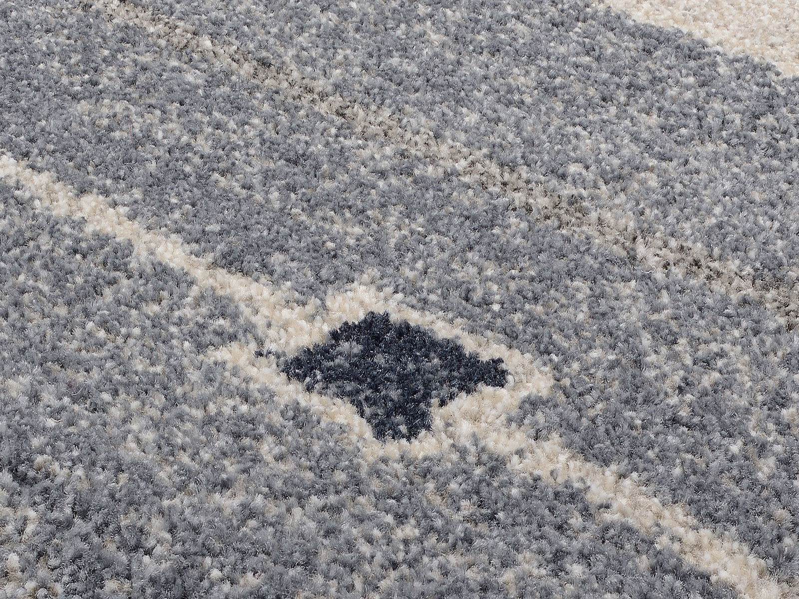 Nahaufnahme eines grauen und cremefarbenen Frisé-Teppichs mit geometrischem Muster.