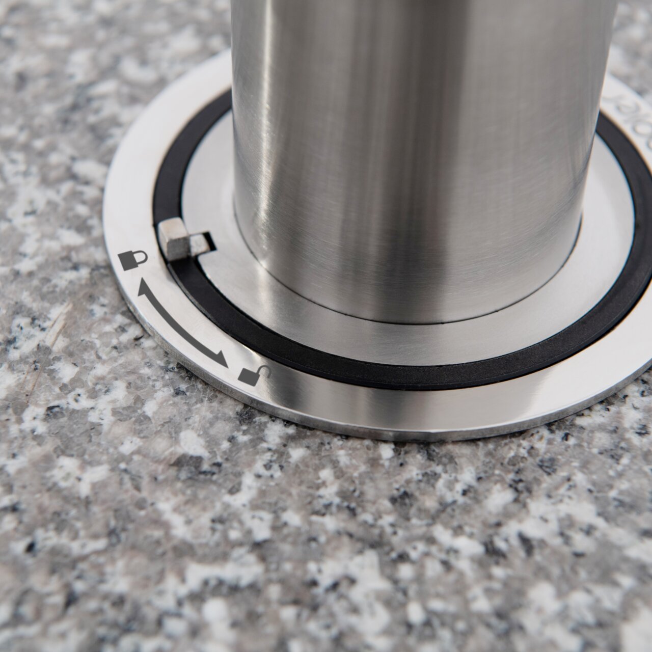 Close-up van een granieten sokkel met roestvrijstalen bevestiging, gezien van bovenaf.