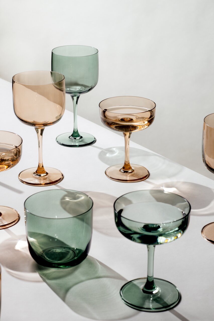 Verschiedene Weinkelche in Grün- und Brauntönen auf einem weißen Tisch, aus der Vogelperspektive fotografiert.