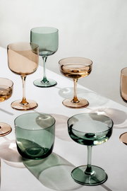 Verschiedene Weinkelche in Grün- und Brauntönen auf einem weißen Tisch, aus der Vogelperspektive fotografiert.