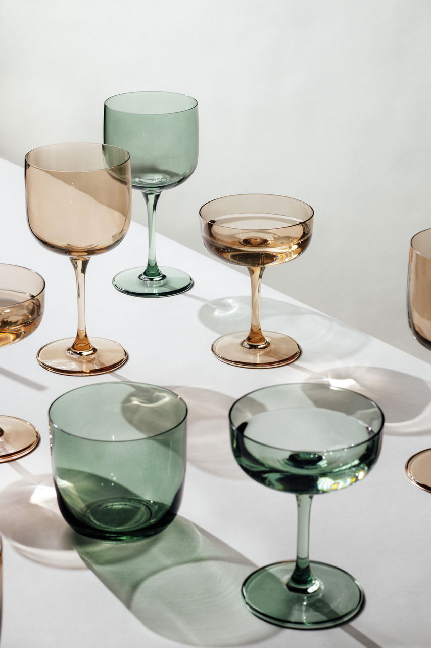 Verschiedene Weinkelche in Grün- und Brauntönen auf einem weißen Tisch, aus der Vogelperspektive fotografiert.