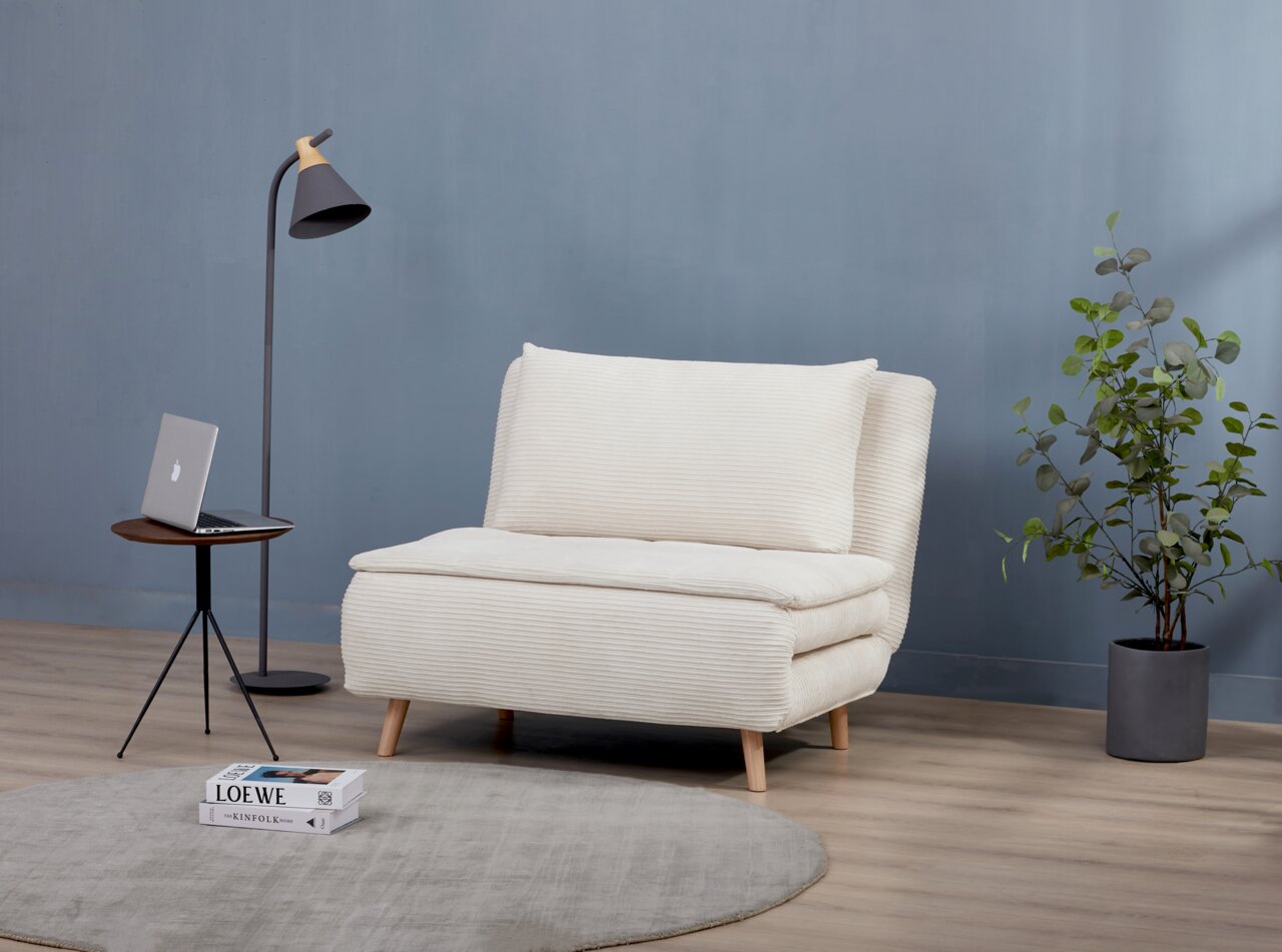 Z2 Functionele fauteuil BEATRICE Een beige functionele fauteuil in een moderne woonkamer, gezien vanaf de zijkant, met een bijzettafeltje, een staande lamp en een plant.
